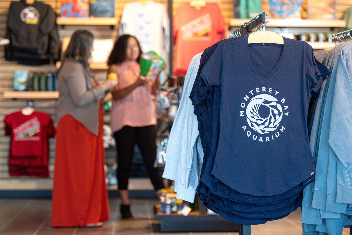 A view of the store with two shoppers in the background and a blue Monterey Bay Aquarium shirt in the foreground